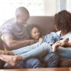 young family of three relax together on living room couch