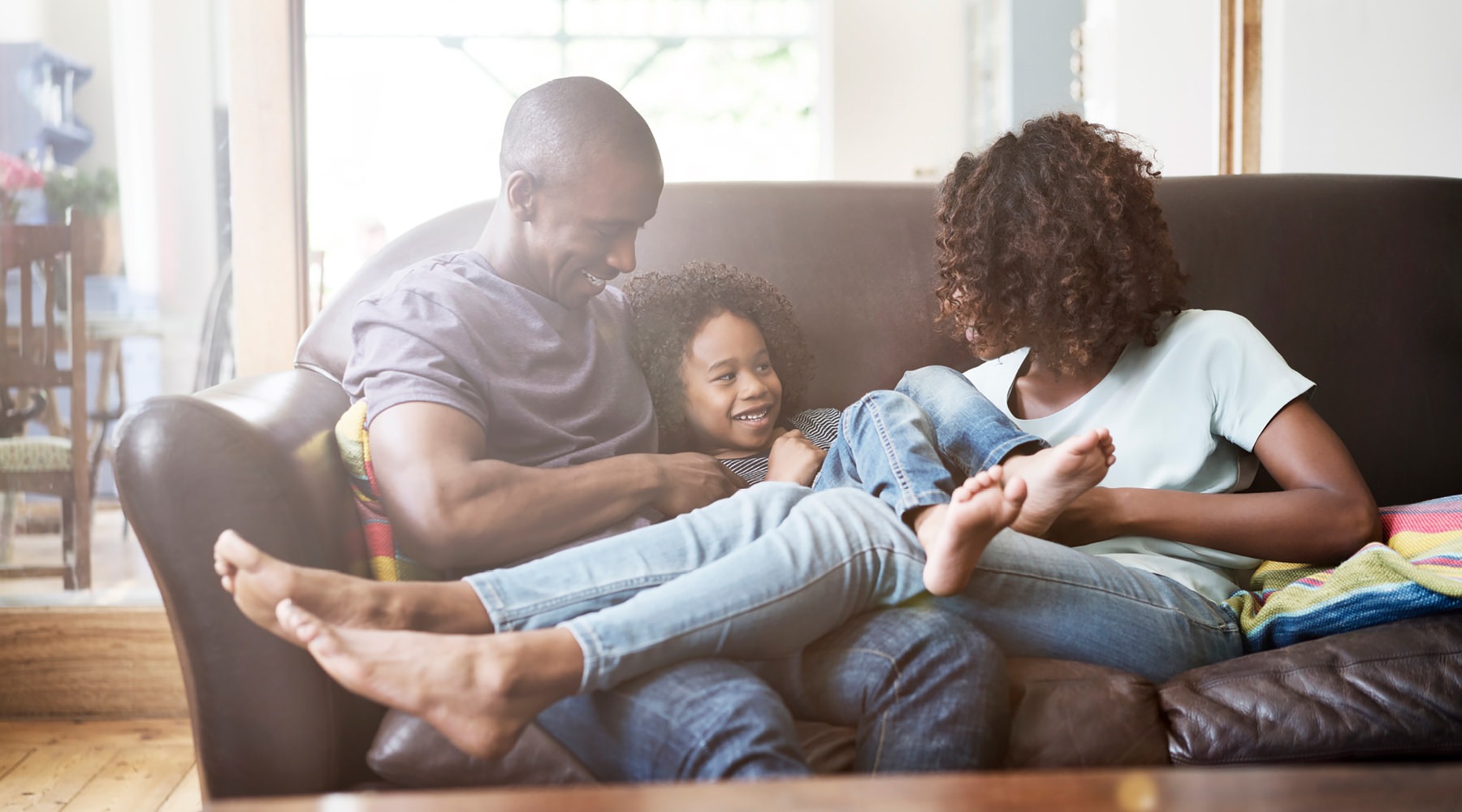 Live Beautifully young family of three relax together on living room couch