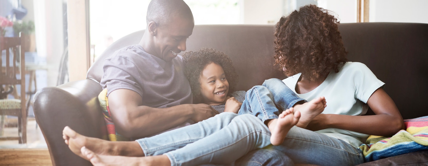 young family of three relax together on living room couch